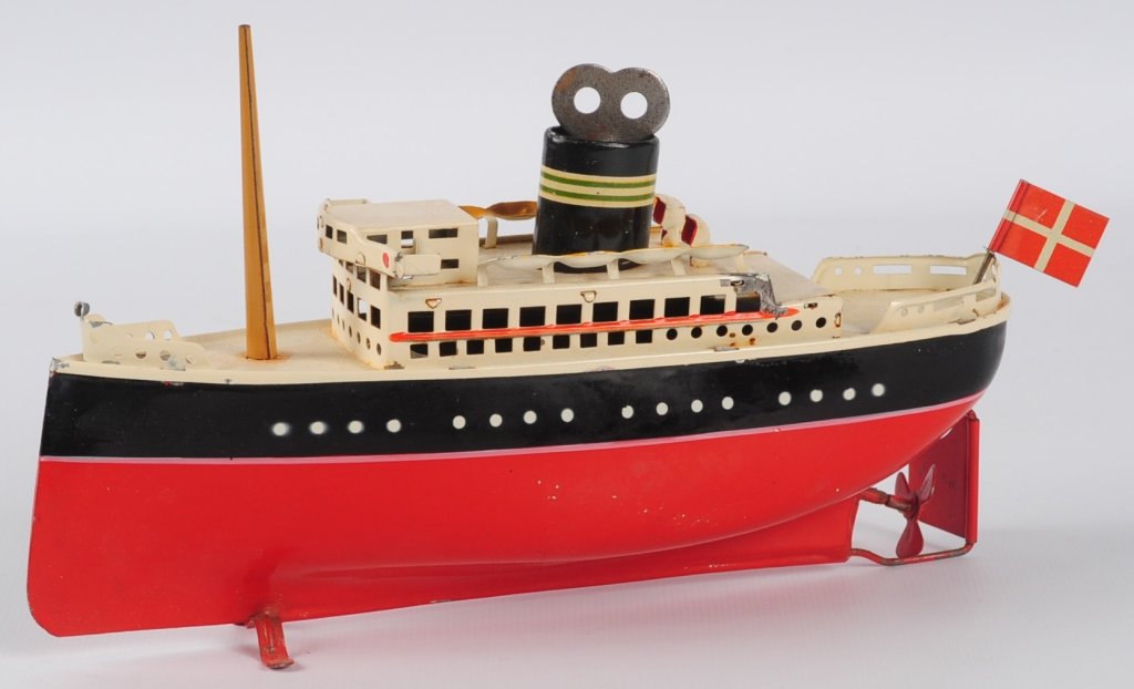 ARNOLD TIN LITHO TOY OCEAN LINER IN ORIGINAL BOX: Red, blue and cream tin litho wind up boat complete with flag pole, two flags, key and box, box marked 'Made in Germany - US Zone', model number 2025/20, ship with flag pole in place measures 5.5 x 9,