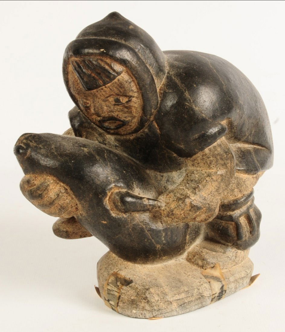 AN INUIT CARVED SOAPSTONE FIGURE OF MAN WITH SEAL (1 of 9)