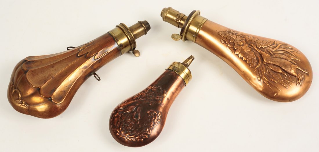 19 C. EMBOSSED COPPER POWDER FLASKS W/ HANGING GAME: Two with embossed design of hanging game, manufacturers name on the brass fitter, sizes range from 5.5 x 2.75 inches up to 8.25 x 3.5 inches.We are happy to offer in-house shipping for all but very la