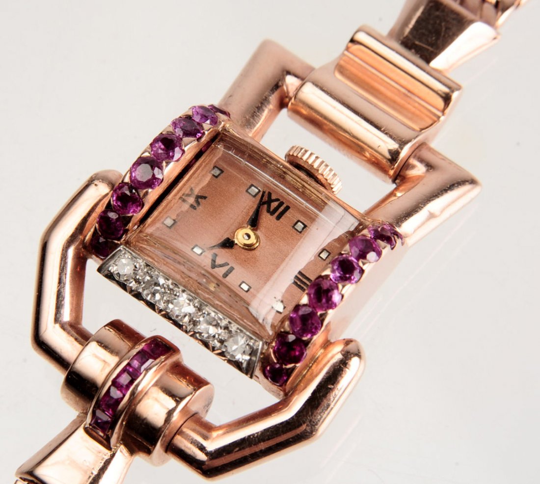 A LADIES' 14K ART MODERNE DIAMOND AND RUBY WATCH: Five diamonds and twenty rubies on the unusual 14 kt gold case and band. The watch measures 1.5 inches, wrist size 6.25 inches, weighs 29 grams. We happily provide seamless, low-cost in-house shipping