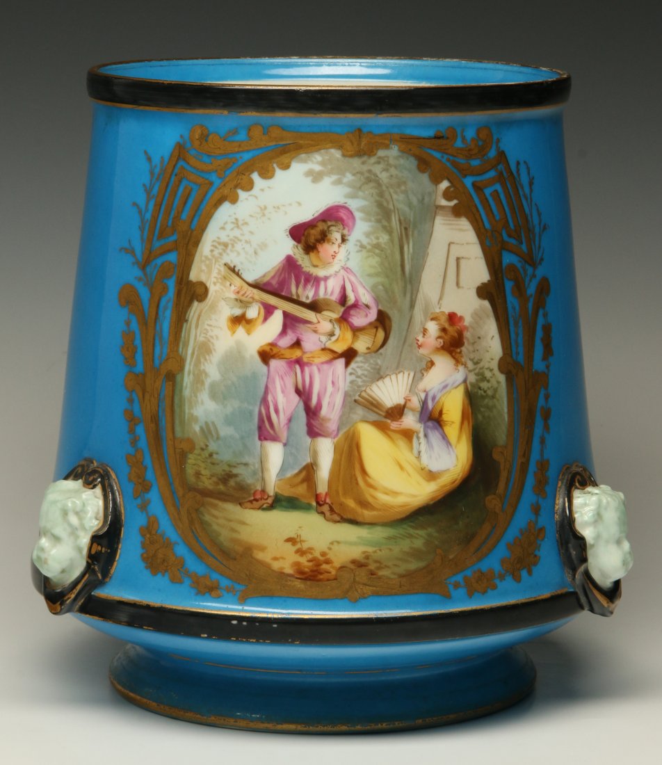 A 19TH CENTURY CONTINENTAL PORCELAIN JARDINIERE: Of tapering form with hand painted decoration of lovers in cartouche front side, the back side with a floral spray, three applied cherub faces in black framing at the waist. Unsigned, measures 8.5 x 7