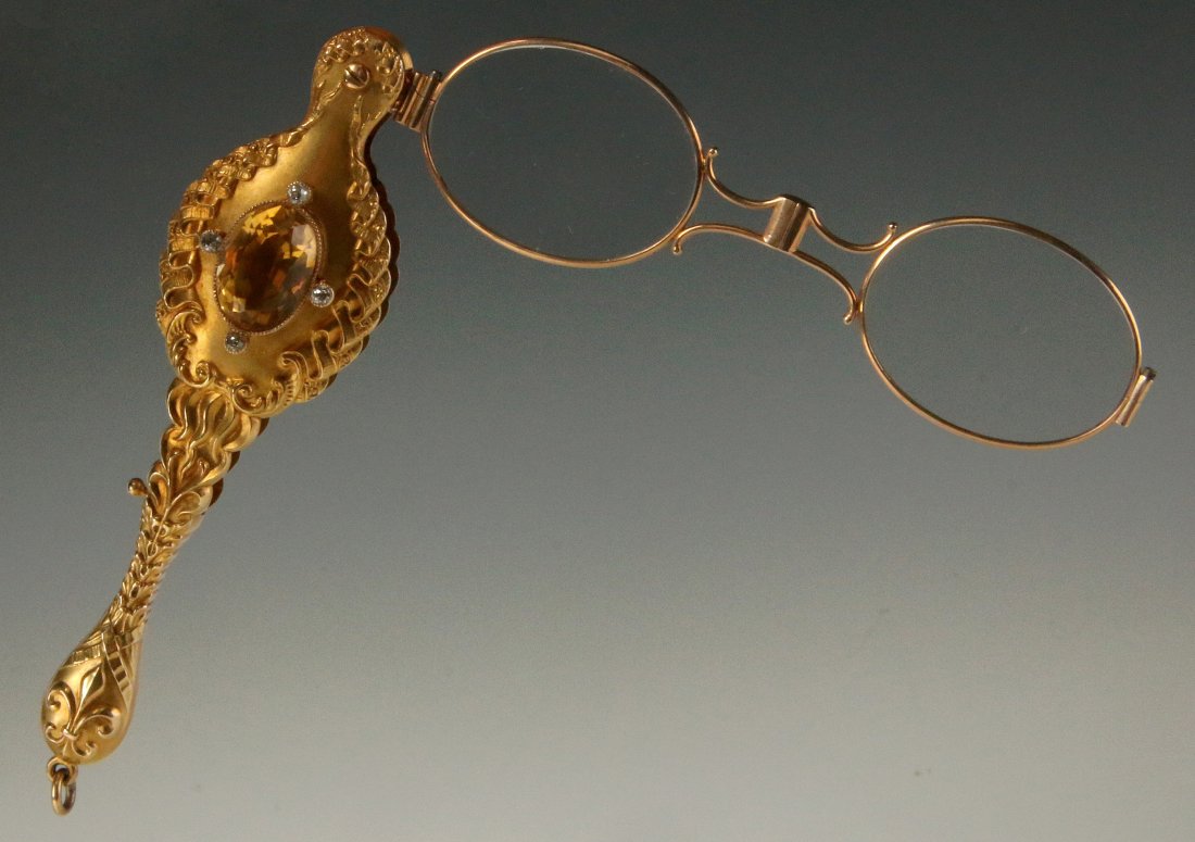 A 14k VICTORIAN LORGNETTE WITH DIAMONDS AND TOPAZ: A fine gold Victorian Lorgnette, the handle adorned with embossed linen fold designs each side of an oval citrine stone framed by four diamonds, the opposite side hand engraved with a swallow-tailed b