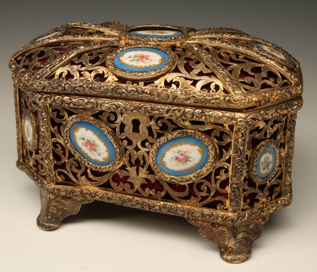 A 20TH CENTURY FILLIGREE METAL JEWELRY CASKET: With floral painted plaques and a later red velvet lining. Measures 5.5 x 8.25 inches.
