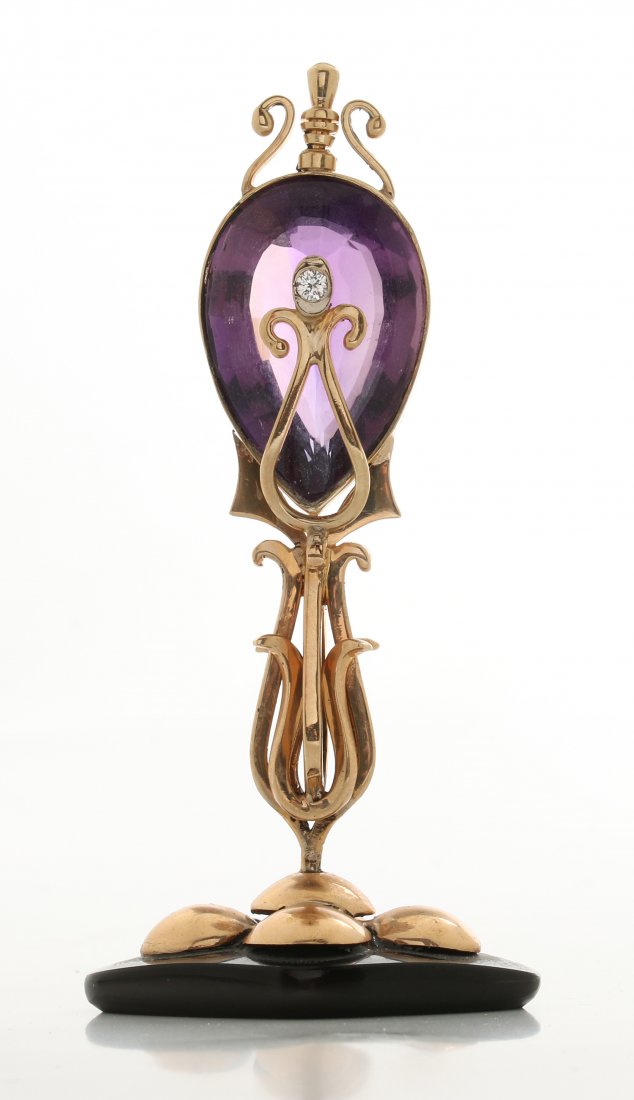 A 14K STAND OR CARD HOLDER WITH BRAZILLIAN AMETHYST: An early 20th c. 14k gold stand with teardrop shape faceted Brazilian Amethyst to an onyx base. The Amethyst measures 25 x 16 mm, stands 3 inches tall, weighs 27 grams.