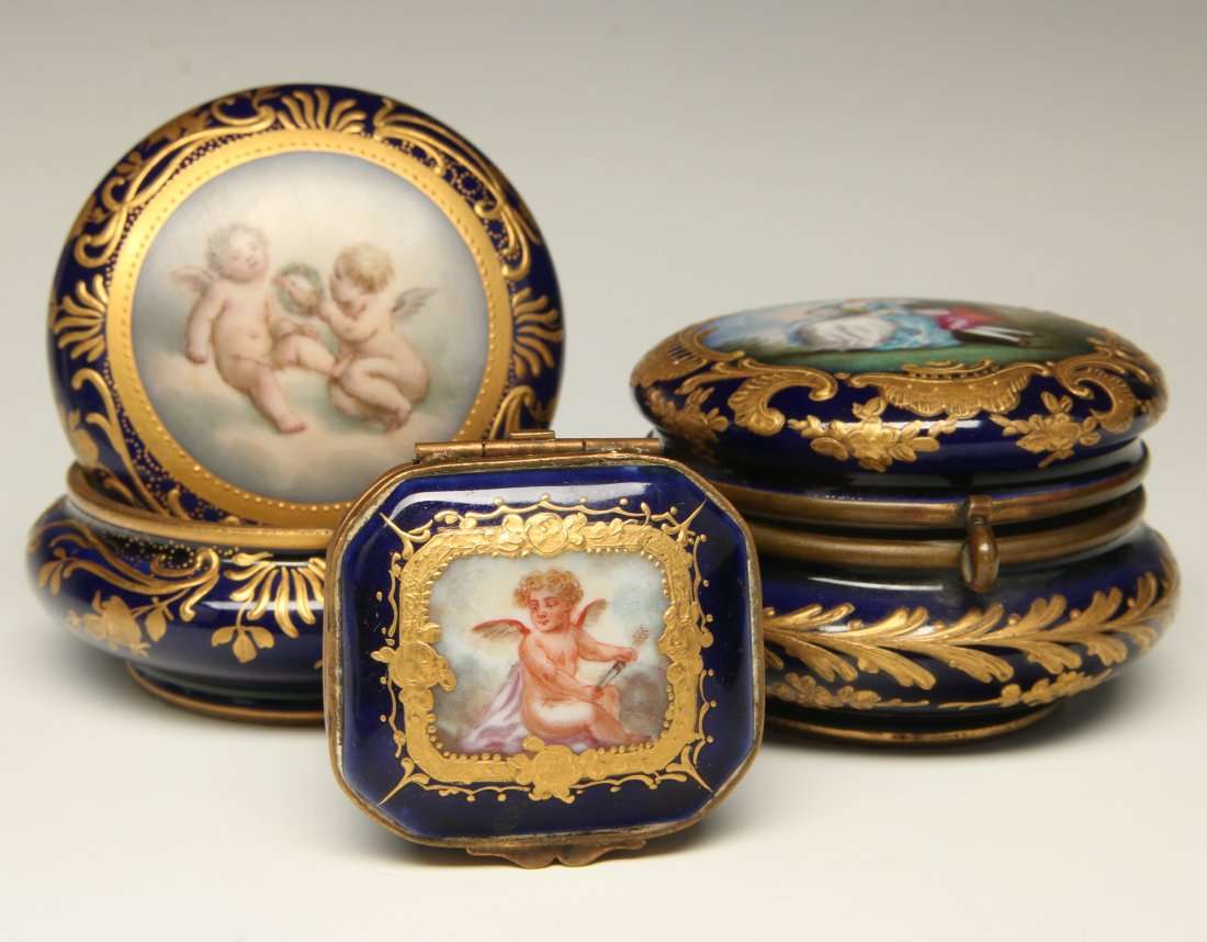 THREE CIRCA 1900 SEVRES PORCELAIN TRINKET BOXES: A squarish box with cherub on the hinged lid, a circular box with romantic scene on the hinged lid and a circular box with convex cover centered by an image of two cherubs. Three Sevres boxes with pai