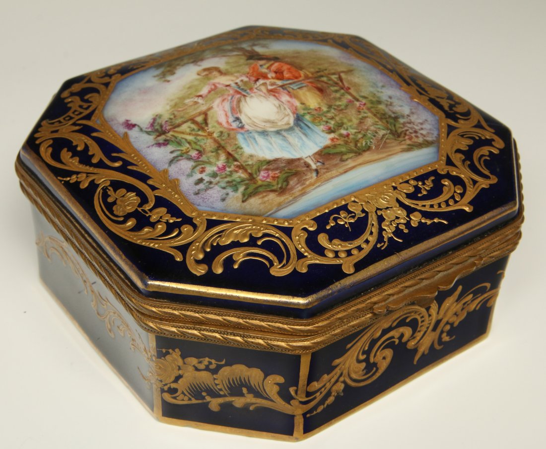 AN EARLY 20TH C. SEVRES STYLE DRESSER BOX: A Sevres style dresser box, the lid decorated with an artist signed hand painted romantic scene artist signed Rolls(?). Measures 2.5 x 6 inches.
