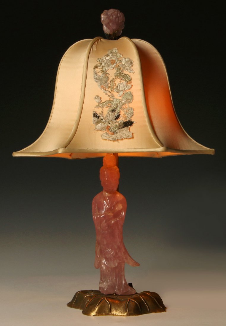 A CHINESE CARVED ROSE QUARTZ FIGURINE TABLE LAMP: A Chinese carved rose quartz figure on ormolu base fitted with an original period embroidered shade. Measures 17.25 x 12 inches, overall to top finial and shade width.