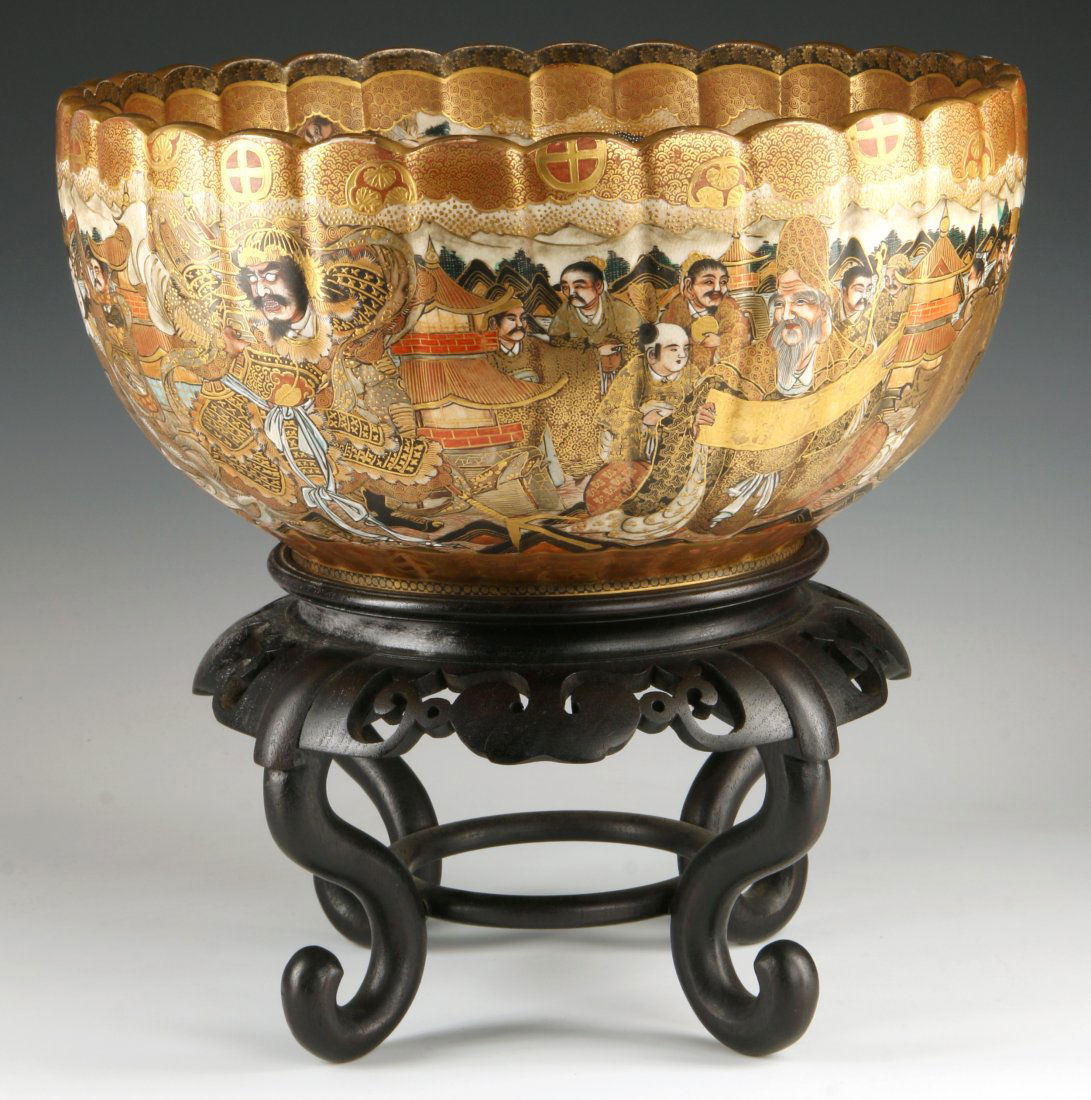 A MEIJI PERIOD JAPANESE SATSUMA EARTHENWARE BOWL: A Japanese Satsuma ware chrysanthemum petal-shaped bowl, Meiji period, late 19th century. Decoration features various popular legendary and religious figures, including Rakan surrounded by golden nimb