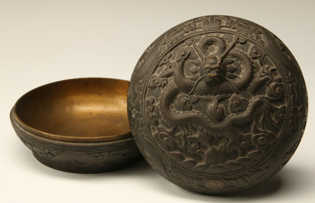 A CHINESE RELIEF MOLDED CIRCULAR BOX WITH DRAGON: A Chinese relief-molded bronze lidded round box with dragon designs; apocryphal 6-character Qianlong base mark. Measures 4 x 5.75 inches.