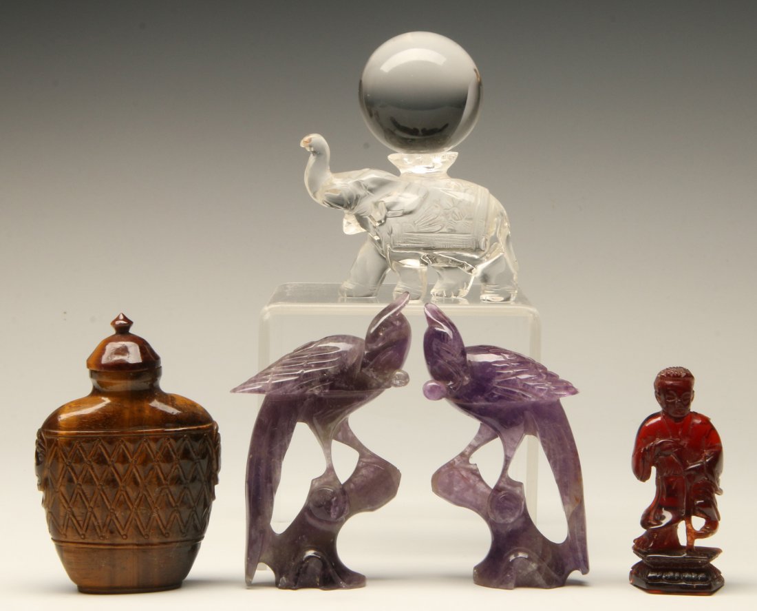 A GROUP OF FOUR CHINESE CARVED HARDSTONE OBJECTS: A Chinese group of four assorted hardstone objects; a pair of amethyst birds, a crystal ball atop an elephant, a brown striated hardstone snuff bottle with net and mask design and ivory spoon, and a c