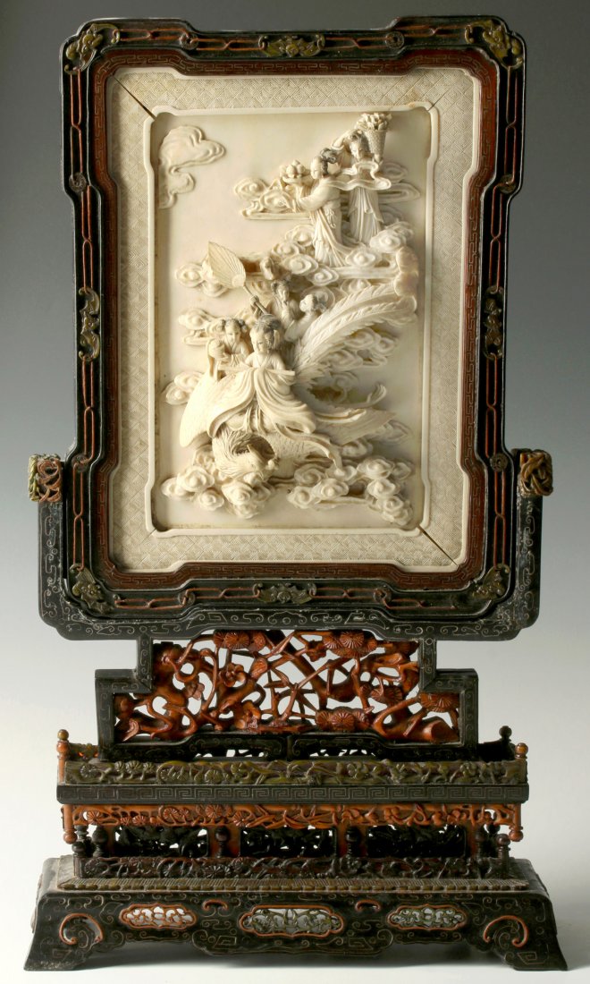 A 19TH C. CHINESE IVORY TABLE SCREEN ON STAND: A Chinese carved hardwood table stand with wire inlay and inset ivory panel carved with celestial maidens in high relief, an inset panel below depicting a floral vine, pierce carvings in the base. Mea
