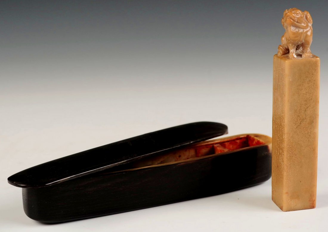 A BOXED CHINESE CARVED HARDSTONE SEAL WITH FU DOG: Chinese, Hardstone seal with carving of Fu Dog; wooden case with cavity for seal ink. Inscriptions to sides. Measures 4.25 x 1 inch.