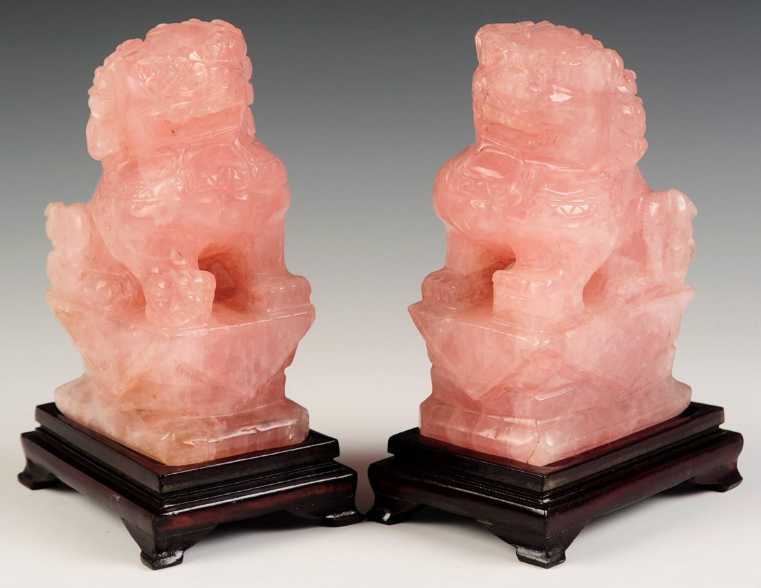 A PAIR OF CHINESE FU DOG ROSE QUARTZ CARVINGS: On wood stands. Each measures 6.25 x 4.25 inches.