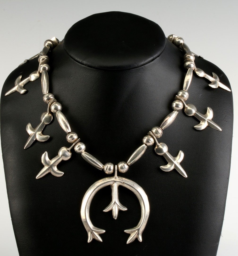 A STERLING SILVER SAND CAST SQUASH BLOSSOM NECKLACE: Unsigned, pendant measures 2.25 x 1.75, necklace length 28 inches.