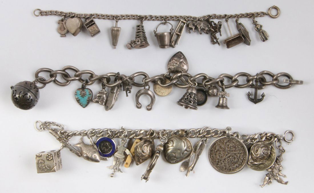 THREE CHARM BRACELETS WITH STERLING CHARMS: The thinnest single link is 6.75 inches long with twelve charms, some sterling. The middle size bracelet is 6.75 inches long with fourteen charms, one marked sterling. The heavy curb link bracelet is