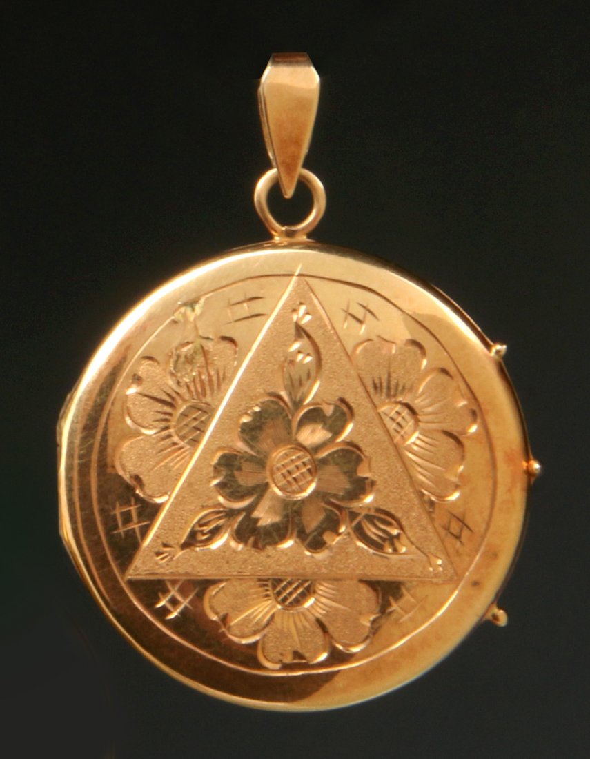 AN 18K GOLD LOCKET: An 18k gold locket with hand engraved decoration, marked on the bail, measures 1.25 inches without the bail, weighs 10.7 grams.