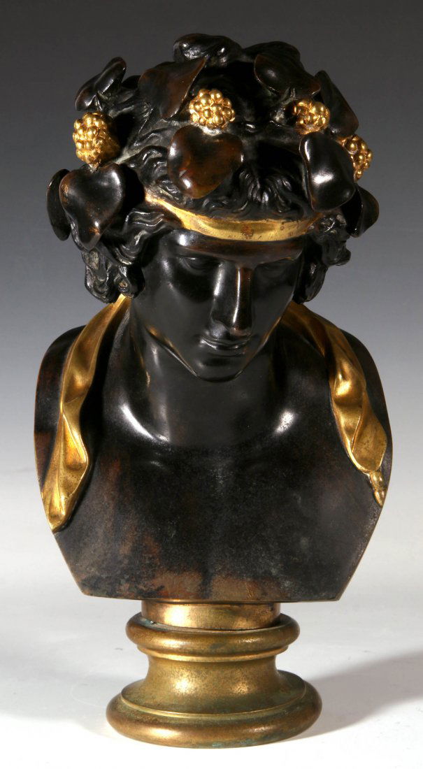 A CIRCA 1900 BRONZE HEAD AFTER THE GREEK ANTIQUE: The bust of a young Bacchus or other follower of Dionysus in dark brown patina with gilt bronze highlighted head band and korymboi berries, raised on a circular plinth, circa late 19th to early 20th c