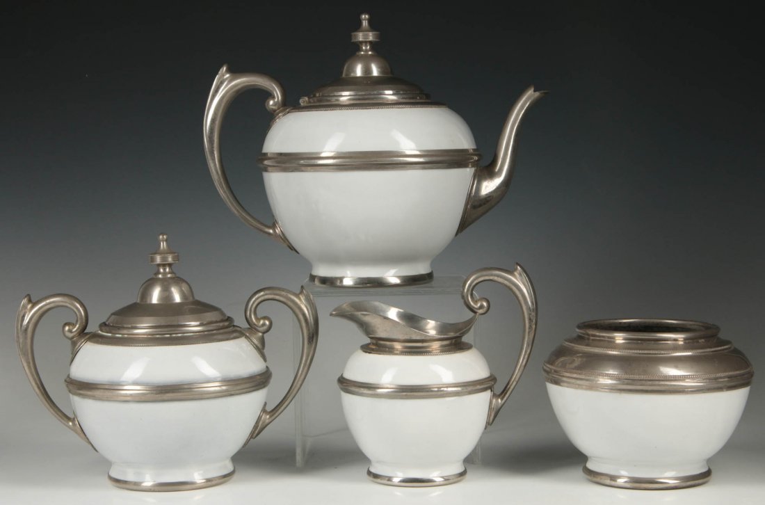 A WHITE GRANITE WARE TEA SET IN PEWTER MOUNTS: An extra clean four piece tea set comprised of Teapot, Creamer, Sugar with lid and Waste bowl. Each piece is extra clean white granite ware. Sizes ranging from 6 x 6 inches to 10.5 x 8.5 inches. We sh