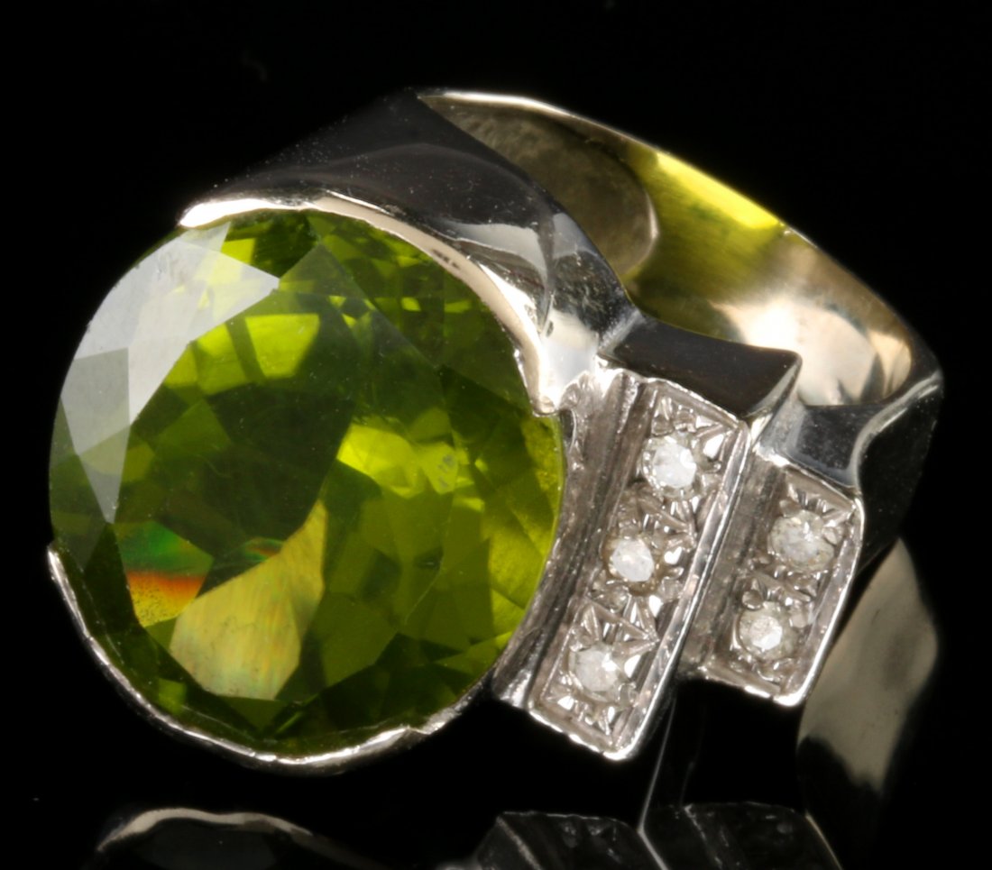 A 14K GOLD GREEN GARNET AND DIAMOND FASHION RING: A large oval green garnet measuring 19 x 16 mm, bezel set in a 14k white gold setting with five side diamonds approximately .03 carat each, marked 14k inside the band, ring size 6, weighs 14 grams. Gu