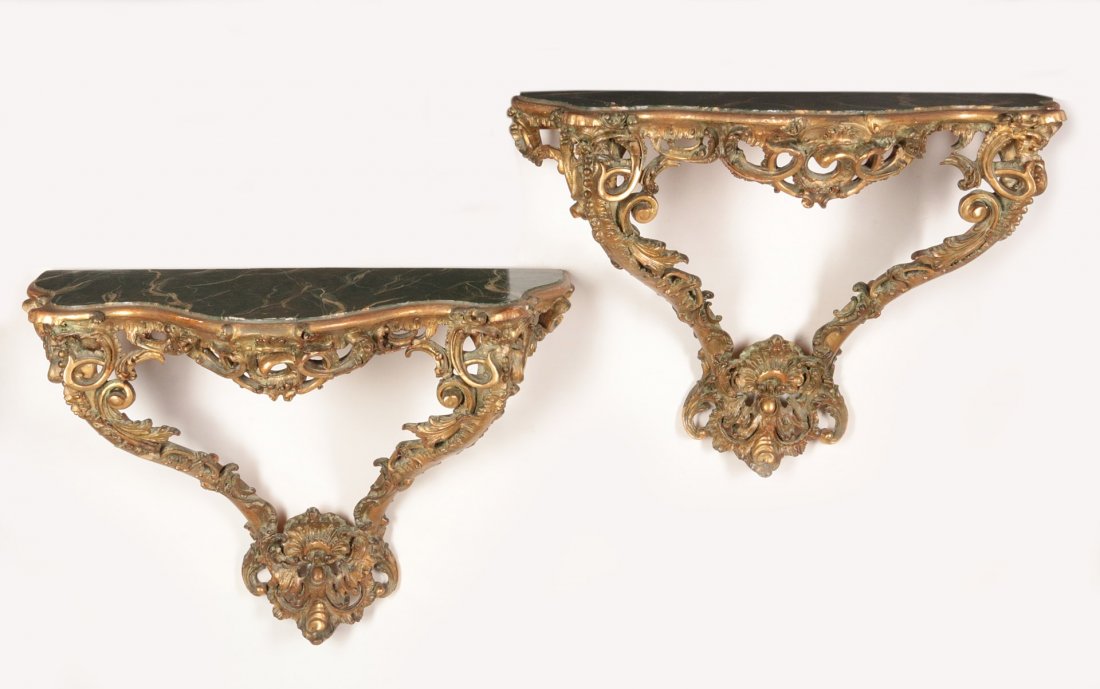 A PAIR C. 1900 BAROQUE STYLE WALL MOUNT CONSOLES: Each having simulated painted marble serpentine top, the frieze carved with scrolls and foliage and centered by a pierced rocaille and acanthine carved scroll, the supports joined by a shell and caboc