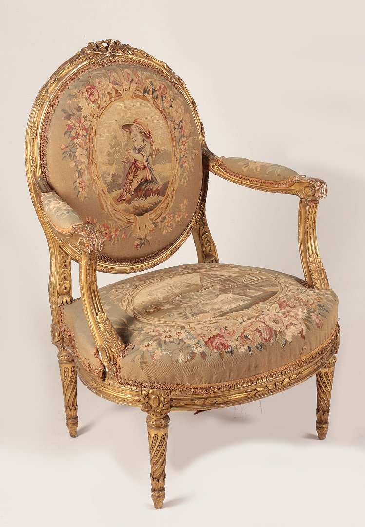 A 19TH C. FRENCH LOUIS XVI AUBUSSON ARM CHAIR: The giltwood medallion leaf-carved and padded back with ribbon crest, curved padded arms with acanthine and channeled carved supports, bowed seat and raised on twisted chandelles d'asperges fluted leg
