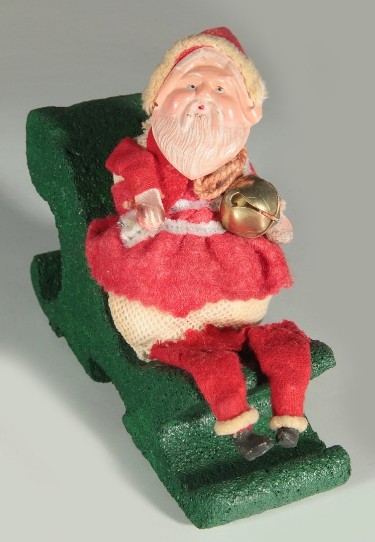 A CEULLOID FACE MESH BODY SANTA CANDY CONTAINER: A tree hanging antique candy container that measures approximatley 5 inches, displayed on a later green stand.