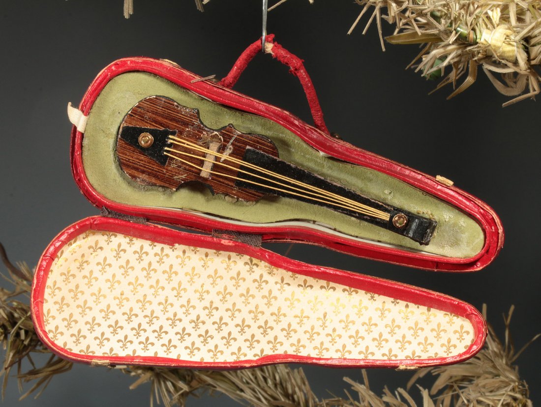 CIRCA 1900 DRESDEN VIOLIN CHRISTMAS ORNAMENT: A three-dimensional miniature violin case opens to reveal an embossed and pieced paper violin with hand-painted details and twine stings, measures 2.5 x 6.5 inches.