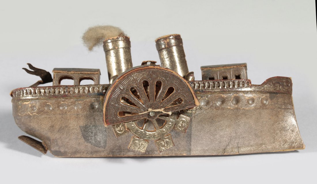 CIRCA 1900 DRESDEN PADDLEWHEEL BOAT ORNAMENT: A three-dimensional embossed and pieced paper ornament with hand-painted polychrome details, paddlewheels turn on a pin axle, cotton wool on one stack to simulate smoke, measures 2 x 4 inches.