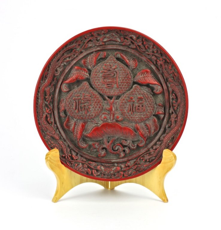 CHINESE CINNABAR PLATE: CHINESE MING DYNASTY CINNABAR PLATE, H 1", DIA 7 5/8":Floral and dragon forms and symbols for happiness, longevity and wealth all in relief. (Da Ming Xuan De Nian Zhi) 6 Characters on underside.