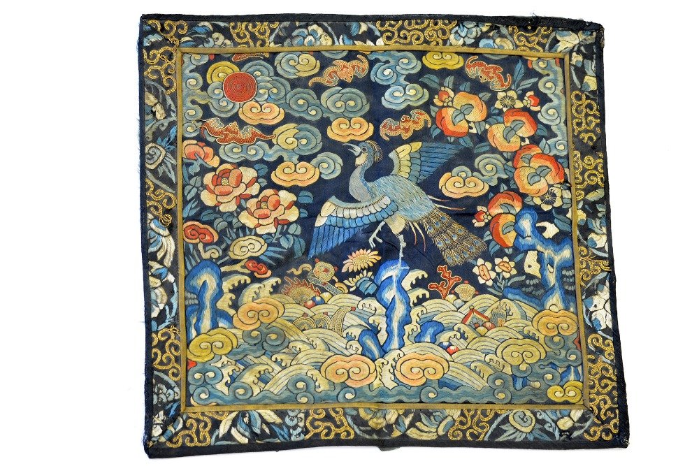 A Chinese Embroidered 'Peacock' Rank Badge: A Chinese Embroidered 'Peacock' Rank Badge, the third rank badge embroidered in silk and couched in gold thread to show a peacock amidst clouds, with minor damage including a small hole and tears to b