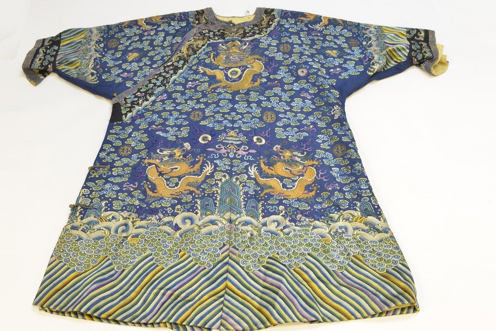 A Chinese Embroidered Dragon Robe: A Chinese Embroidered Dragon Robe, the winter weight robe embroidered and couched in gold thread with five claw dragons on a blue ground above lishui stripe, with minor damage, tears to button clasps,