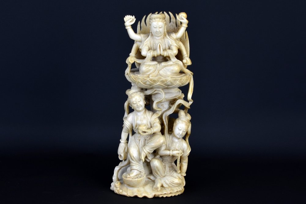 A Chinese Carved Ivory Guanyin Group: A Chinese Carved Ivory Guanyin Group, the tiered ivory statue depicting a six armed Guanyin seated in the lotus position on a lotus throne above two other figures of Guanyin, one represented holding a
