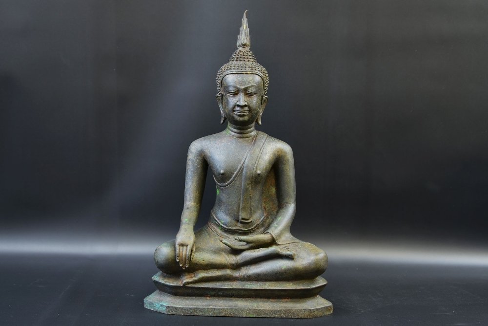 A 16th Century Bronze Figure of Buddha, Nepal: A 16th Century Bronze Figure of Buddha, Nepal, the Buddha seated in virasana with hands in bhumisparsha mudra, the face in a meditative expression with full lips, and heavy-lidded eyes beneath arched 