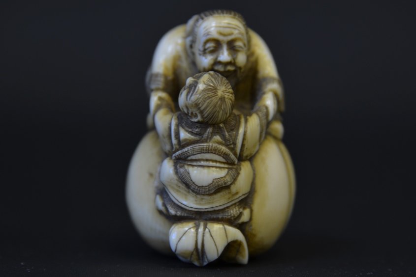 A Japanese Ivory Netsuke, Edo Period: A Japanese Ivory Netsuke, Edo Period, depicting a pair of figures on a large peach, signed to the reverse, with crack, appx. 1 3/4 in. H.