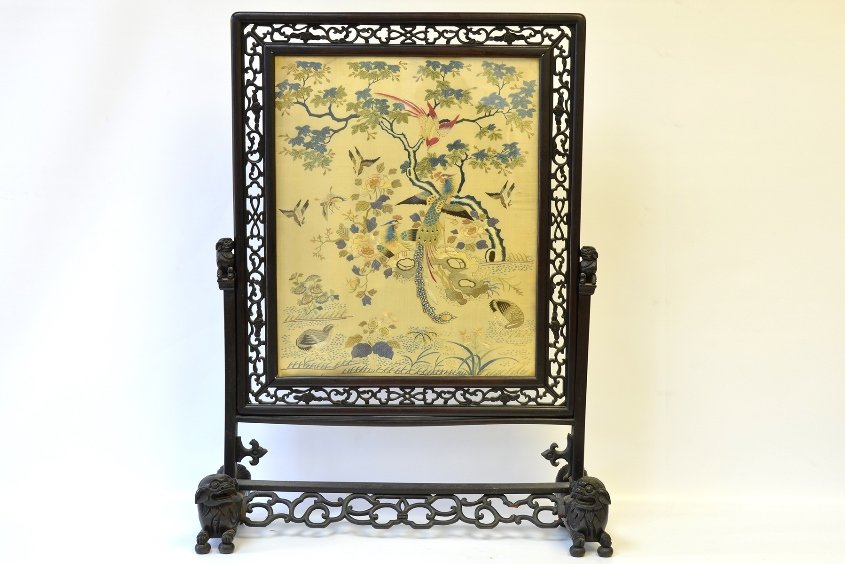 19th Century Chinese Embroidered Table Screen: 19th Century Chinese Embroidered Table Screen, the pierced wood table screen with framed picture of birds in a landscape embroidered in colored silks, on a pierced wood stand with foo dog finials and 