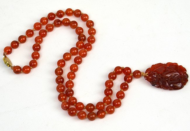 A Chinese Carnelian Necklace: A Chinese Carnelian Necklace, the necklace of carnelian beads suspending a carnelian pendant carved as gourds with flowering tendrils, the pendant appx. 1 7/8 in. H.