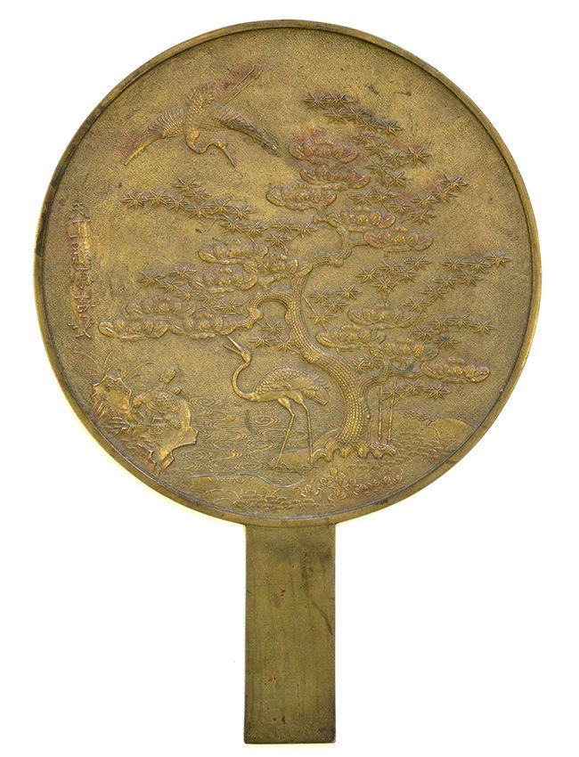 A Japanese Metal Hand Mirror: A Japanese Metal Hand Mirror, with a scene carved in low relief of cranes, a bonsai tree and signature to the left, with scratches to surface, appx. 13 1/8 in. L.