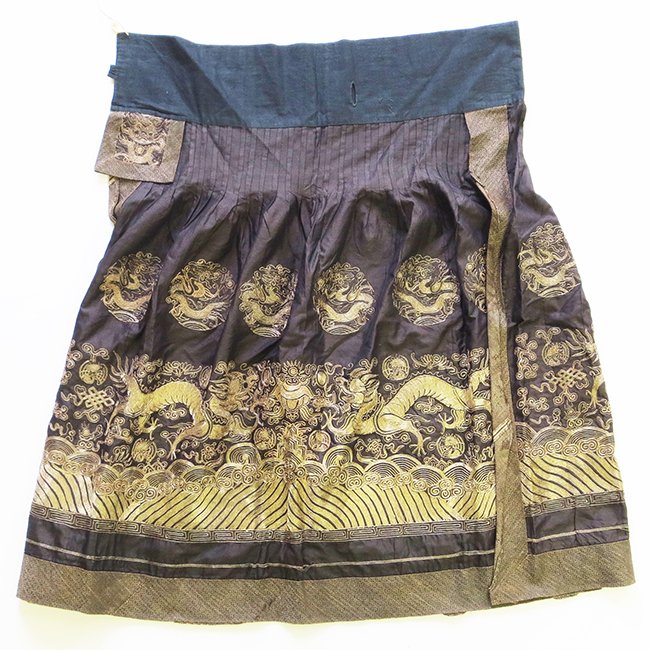 A Chinese Embroidered Skirt: A Chinese Embroidered Skirt, the plum skirt couched in gold thread to show dragon medallions above confronting dragons chasing a flaming pearl above rolling waves, appx. 39 in. H.