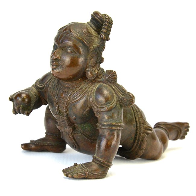 An Indian Bronze Figure of Balakrishna: An Indian Bronze Figure of Balakrishna, the baby Krishna wearing chains around his waist and a necklace, his face with a humorous expression, holding a ball of butter in his right hand, appx. 3 1/3 in