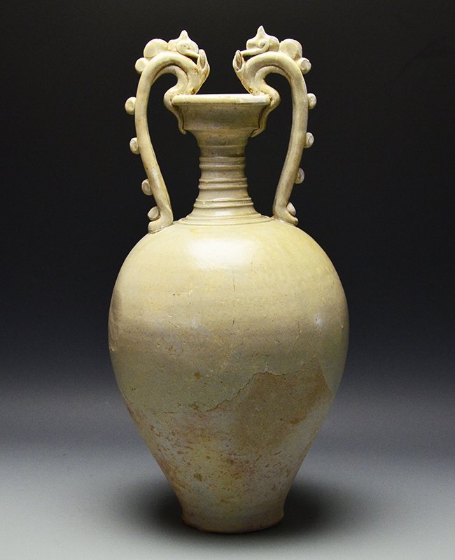 A Chinese Straw-Glazed Stoneware Amphora, Tang: A Chinese Straw-Glazed Stoneware Amphora, Tang Dynasty, the tapering ovoid vessel with a pair of sinuous dragon handles rising from the shoulder to bite the cup of the ribbed neck, the handles mounted