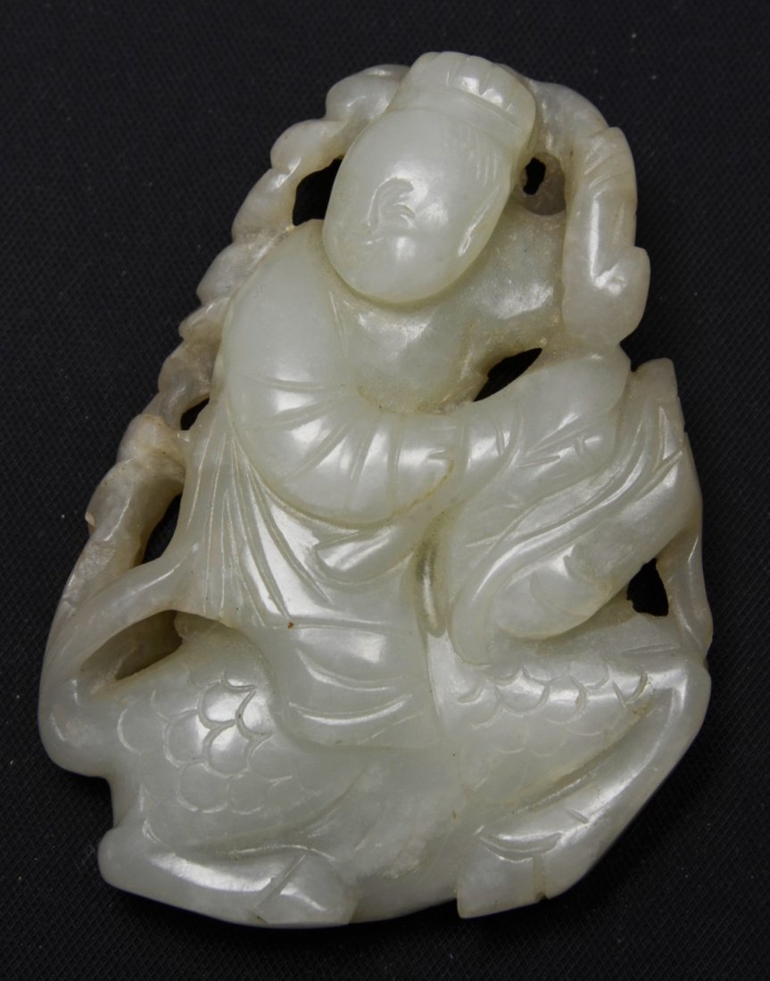 A Chinese White Jade Carving of a Youth on a Qilin: A Chinese White Jade Carving of a Youth on a Qilin, 19th century, the youth holding a lotus sprig over their shoulder with one hand and a mouth organ in the other, riding a qilin, symbolic of a wish f