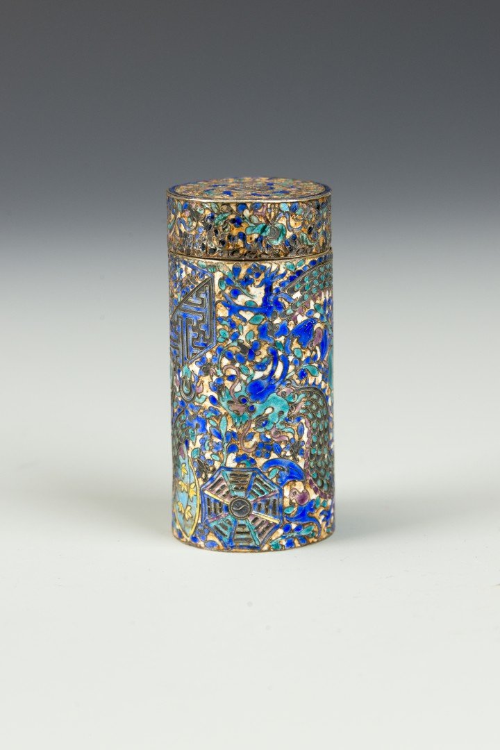 A Small Chinese Silver Enameled Cylindrical Box: 19th century, Qing dynasty The tall cylindrical silver lidded box decorated in blue, green, white, yellow and purple enamels to depict a dragon, the bagua, a lion, coins, a vase with flowers and other