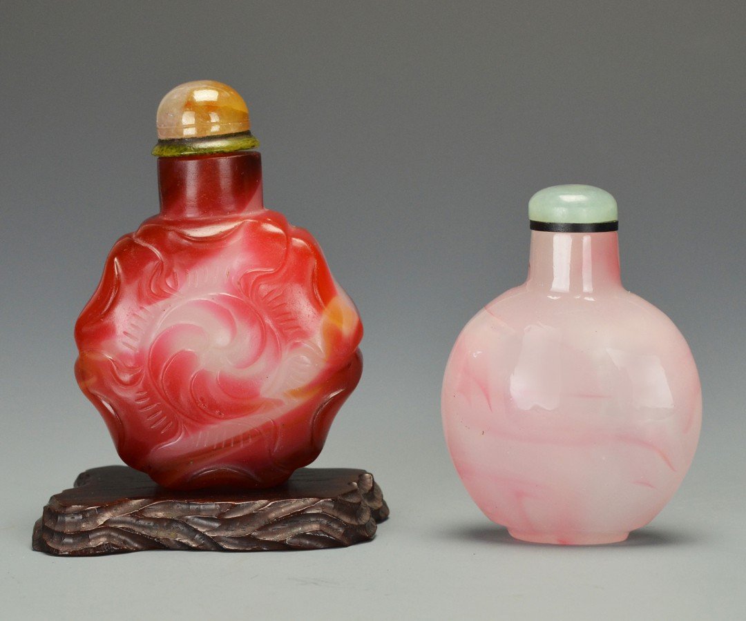 A Lot of Peking Glass Snuff Bottles: One flattened round stuff bottle made of pink swirled glass with green jade top and spoon. Approx. 2 1/4 by 1 1/2 in., 6 by 4 cm. The second red and white swirled Peking glass carved into the shape of