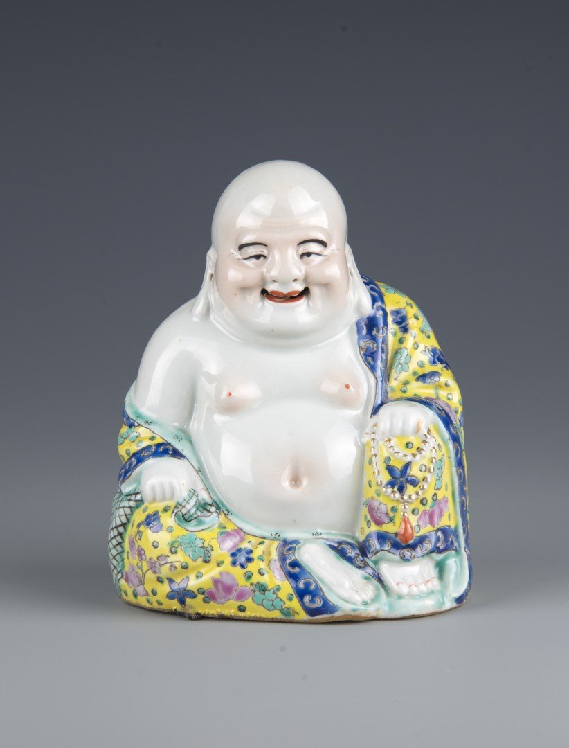 A Chinese Porcelain Famille Rose Figure of a Budai: The jovial buddha is seated with his left knee up, his left hand resting on the knee holding a string of jewels and his body draped in a robe with enamel flowers and butterflies, in a famille rose pal