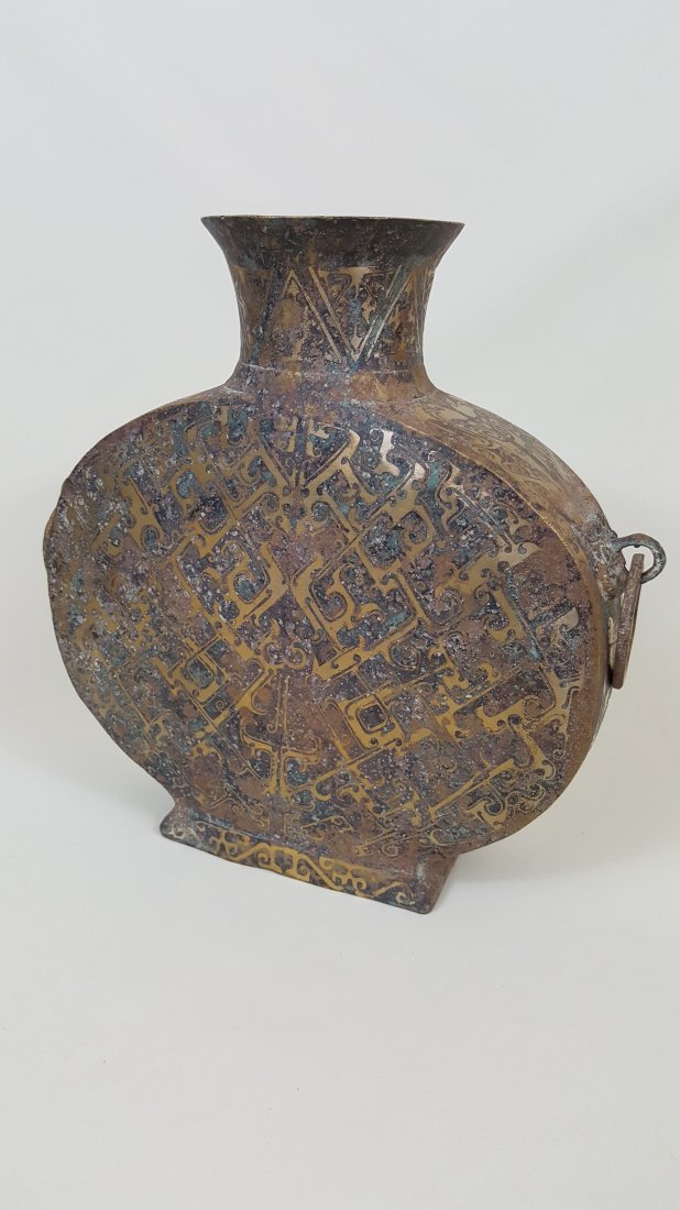 A Bronze with Silver Inlay Wine Flask Zhou Dynasty: A late E. Zhou dynasty bronze bianhu, flat Hu shape flask with silver inlay geometric decoration and beast face mask depictions and two ring handles on the sides. Late Warring States period. 9"Hx 9"Wx