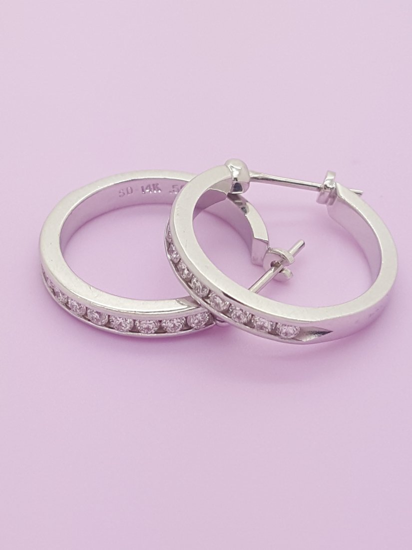 A Pair of 14k White Gold Diamond Hoop Earrings: A pair of 14k white gold diamond hoop earrings in post back style, bearing 0.50 cwt. of channel set round diamonds. Total weight of earrings is 3.7 grams.