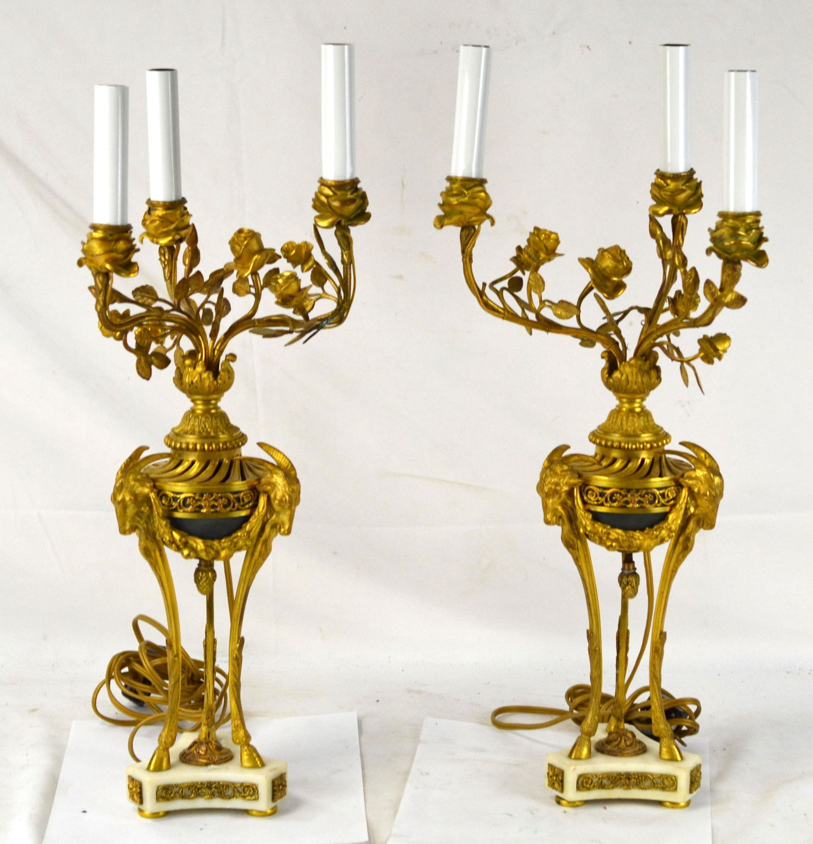 Pr Dore Bronze Ram Head Candelabras: Pair of French dore bronze candelabras with white marble base. each decorated with three ram heads on middle section, with rose on leaf branch and three lights. 20 3/4"H x 8"W