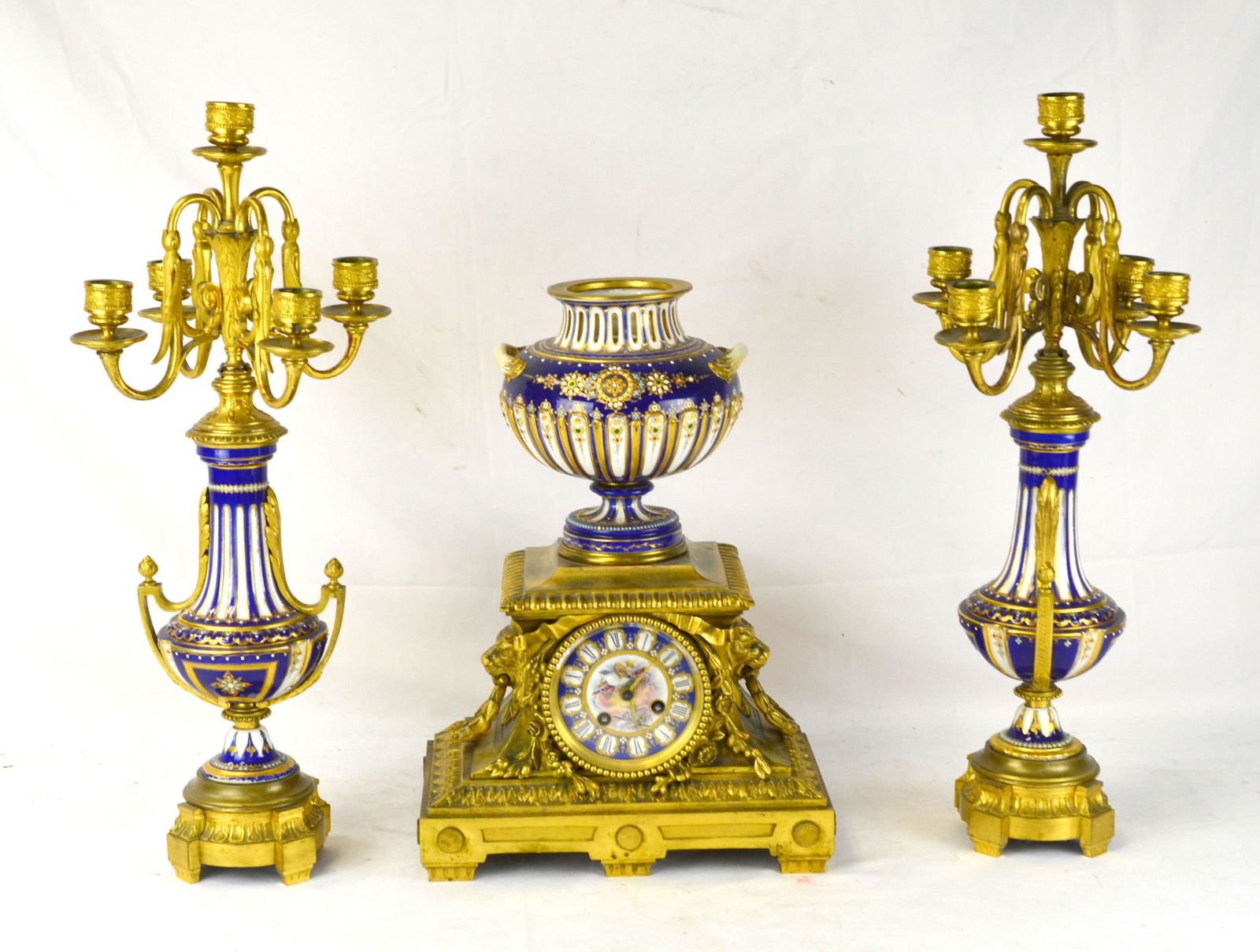 Fine Three Pcs Sevres Jeweled Bronze Clock Set: Fine Three pieces of Sevres Jewelled clock set including a clock with bronze bottom and a jeweled vase on top. size: 15"H x 11"W, and pair of candle sticks with four hand holders. 20"H x 8 1/4"W