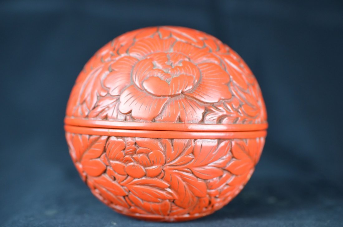 A Chinese Carved Red Laquer Round Shaped Box: This carved Red Laquer box splts in the middle and opens up to reveal a painted black inside. Small cracks throughout.has been broken to pieces and reguled back check the photoes before bidding. 4' H
