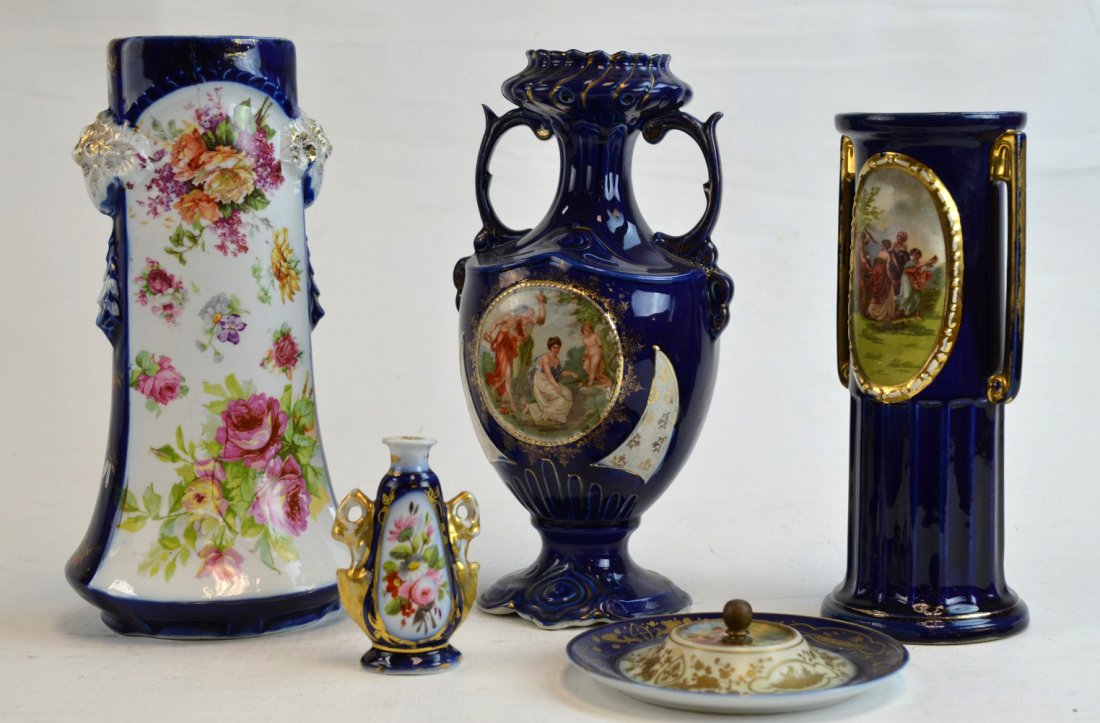 Four Porcelain Vases Painted with Classical Design: Four porcelain vases painted with flowers or Classical scenes against a deep blue ground with gilded accents, together with a handled ring dish. Repair to one, crack to another vase. Tallest: 12''
